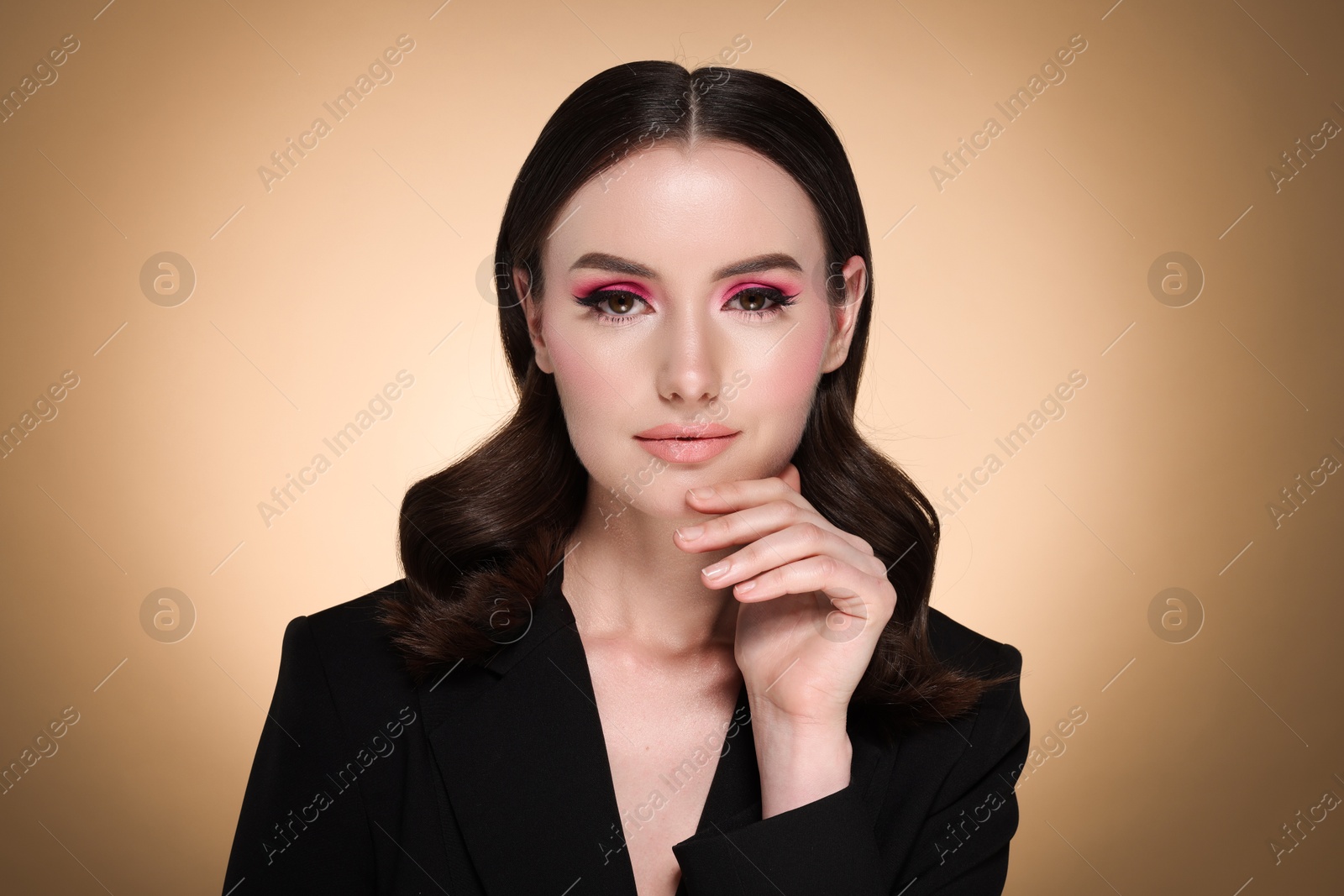 Photo of Portrait of beautiful young woman with stylish makeup and gorgeous hair on beige background