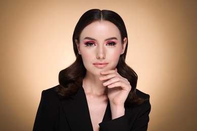 Portrait of beautiful young woman with stylish makeup and gorgeous hair on beige background