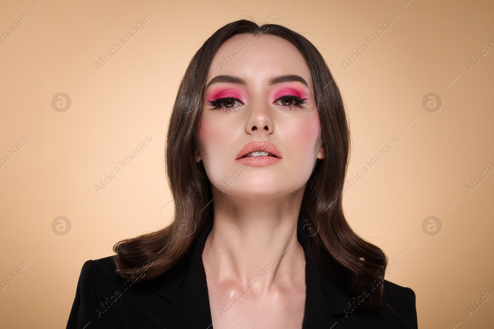 Photo of Portrait of beautiful young woman with stylish makeup and gorgeous hair on beige background