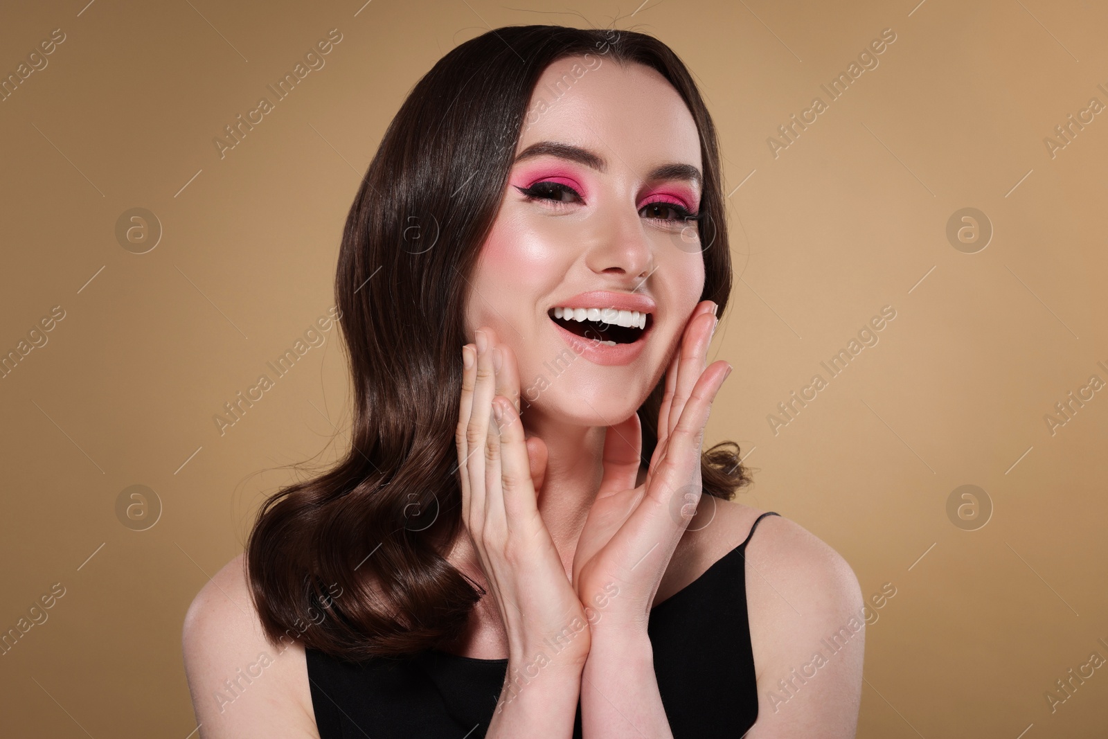 Photo of Portrait of beautiful young woman with stylish makeup and gorgeous hair on beige background