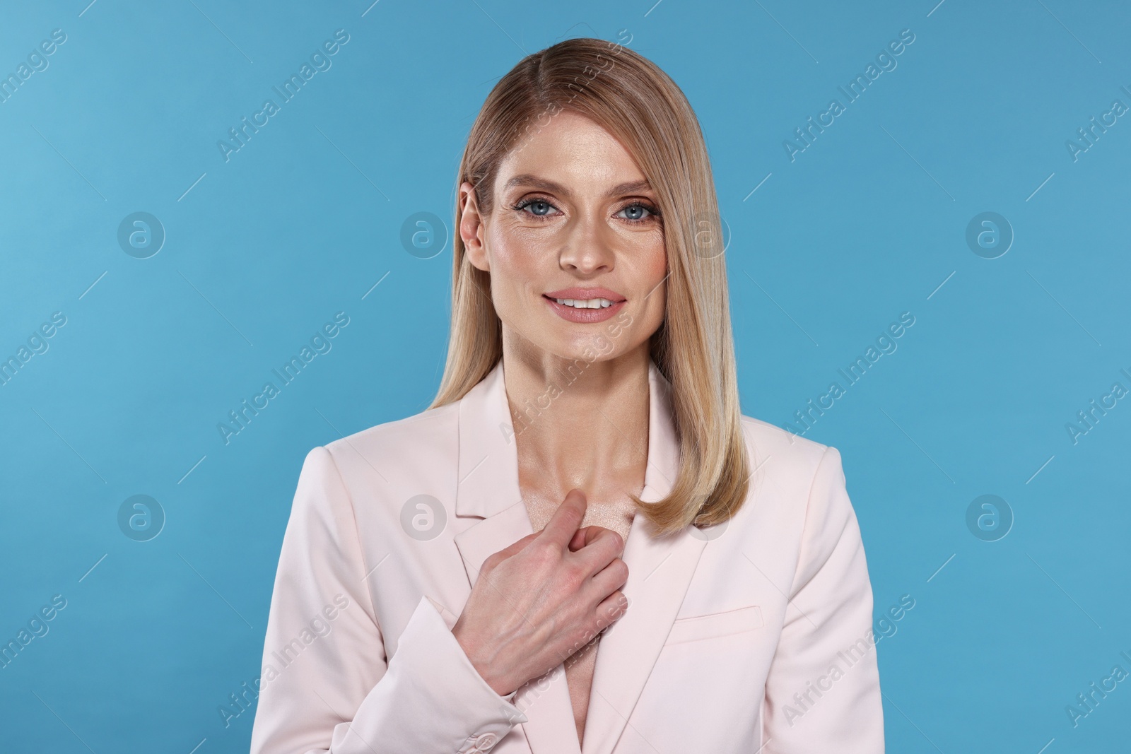 Photo of Portrait of beautiful happy woman with straight blonde hair on light blue background