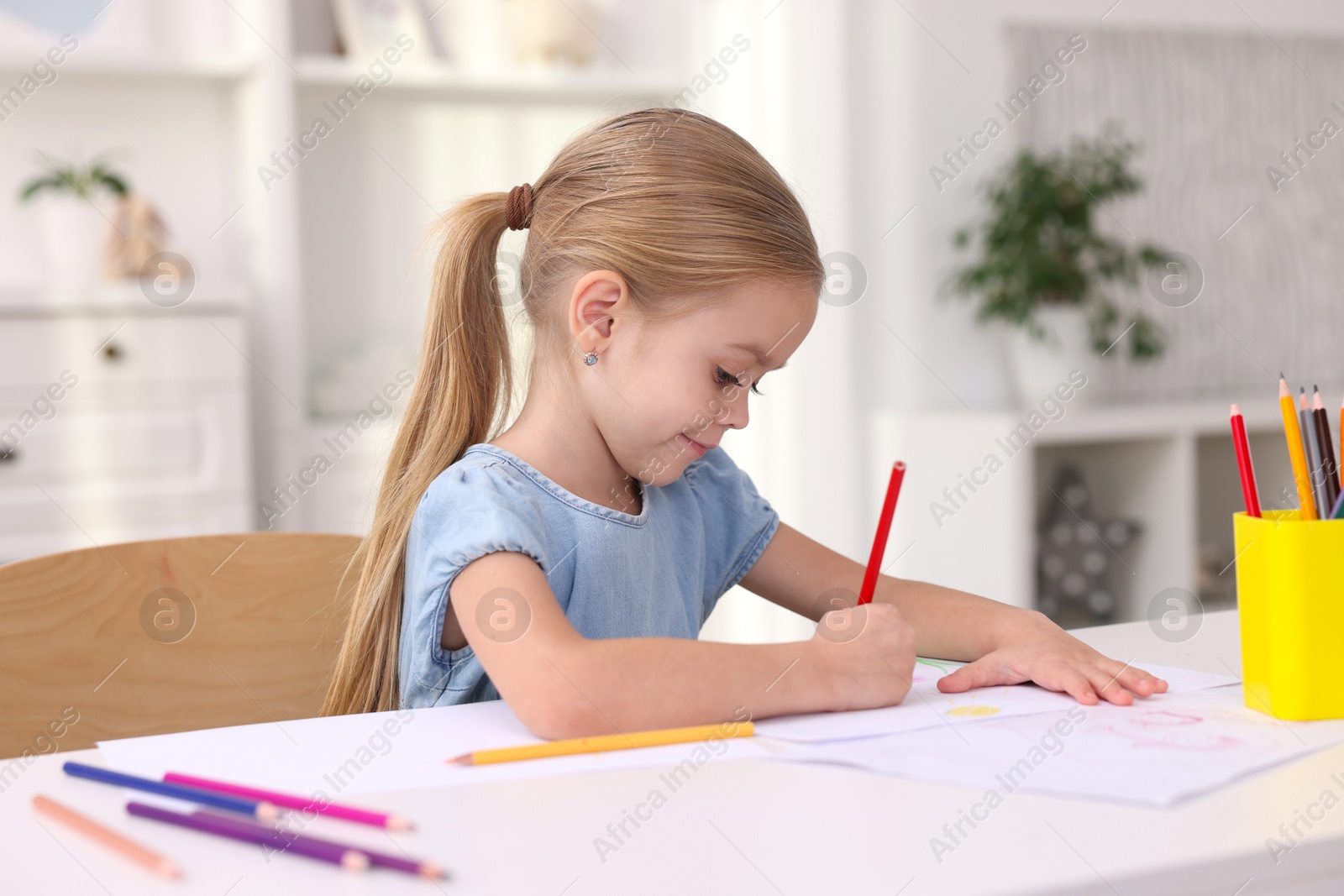 Photo of Cute girl drawing at white table in kindergarten