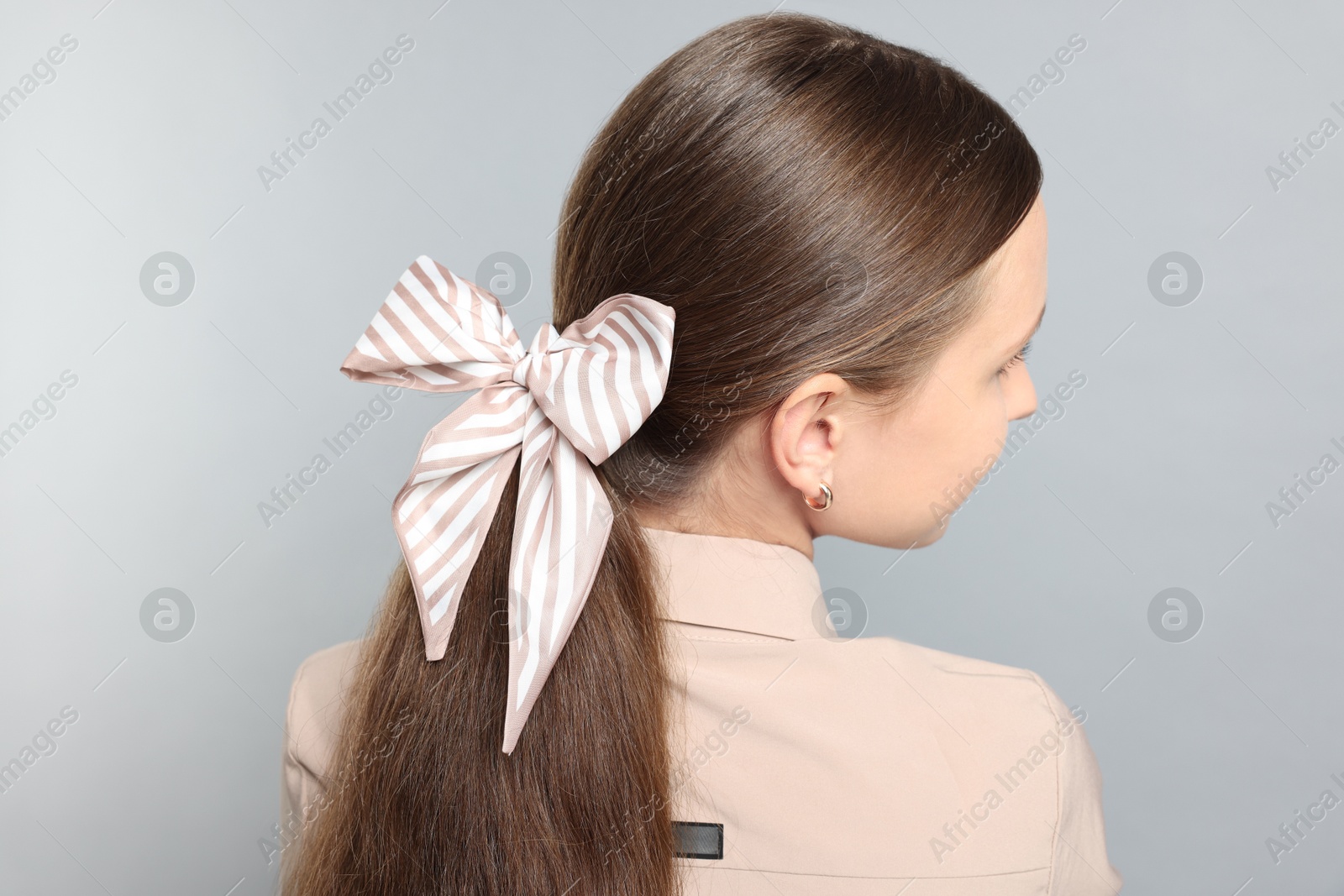 Photo of Teenage girl with stylish hair band on light grey background, back view