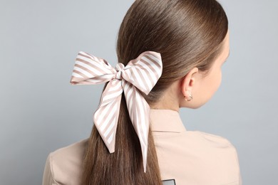 Photo of Teenage girl with stylish hair band on light grey background, back view