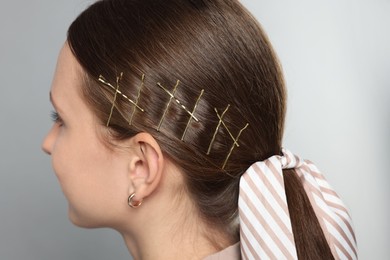 Photo of Teenage girl with stylish hair clips and bandana on light grey background, closeup