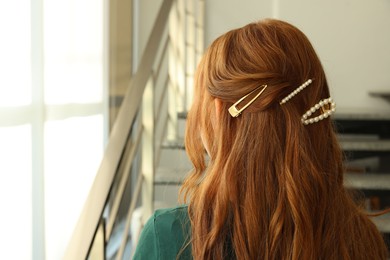 Photo of Teenage girl with stylish hair clips indoors, back view. Space for text