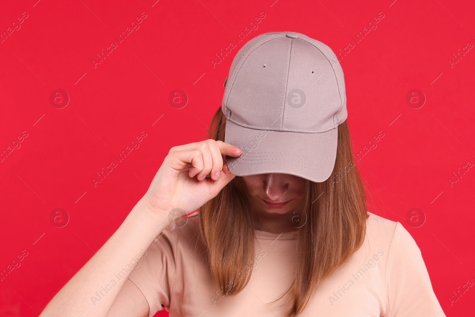 Photo of Woman in stylish baseball cap on red background. Mockup for design