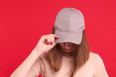 Photo of Woman in stylish baseball cap on red background. Mockup for design