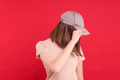 Photo of Woman in stylish baseball cap on red background. Mockup for design