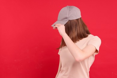 Photo of Woman in stylish baseball cap on red background. Mockup for design