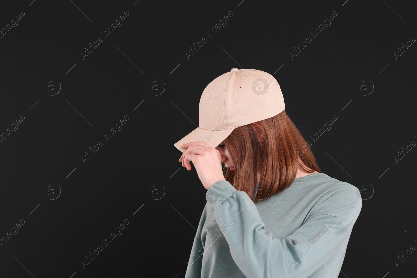 Photo of Woman in stylish baseball cap on black background. Mockup for design