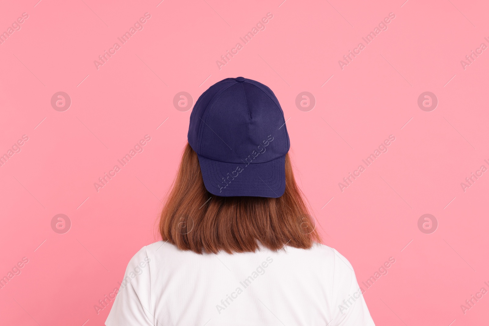 Photo of Woman in stylish baseball cap on pink background, back view. Mockup for design