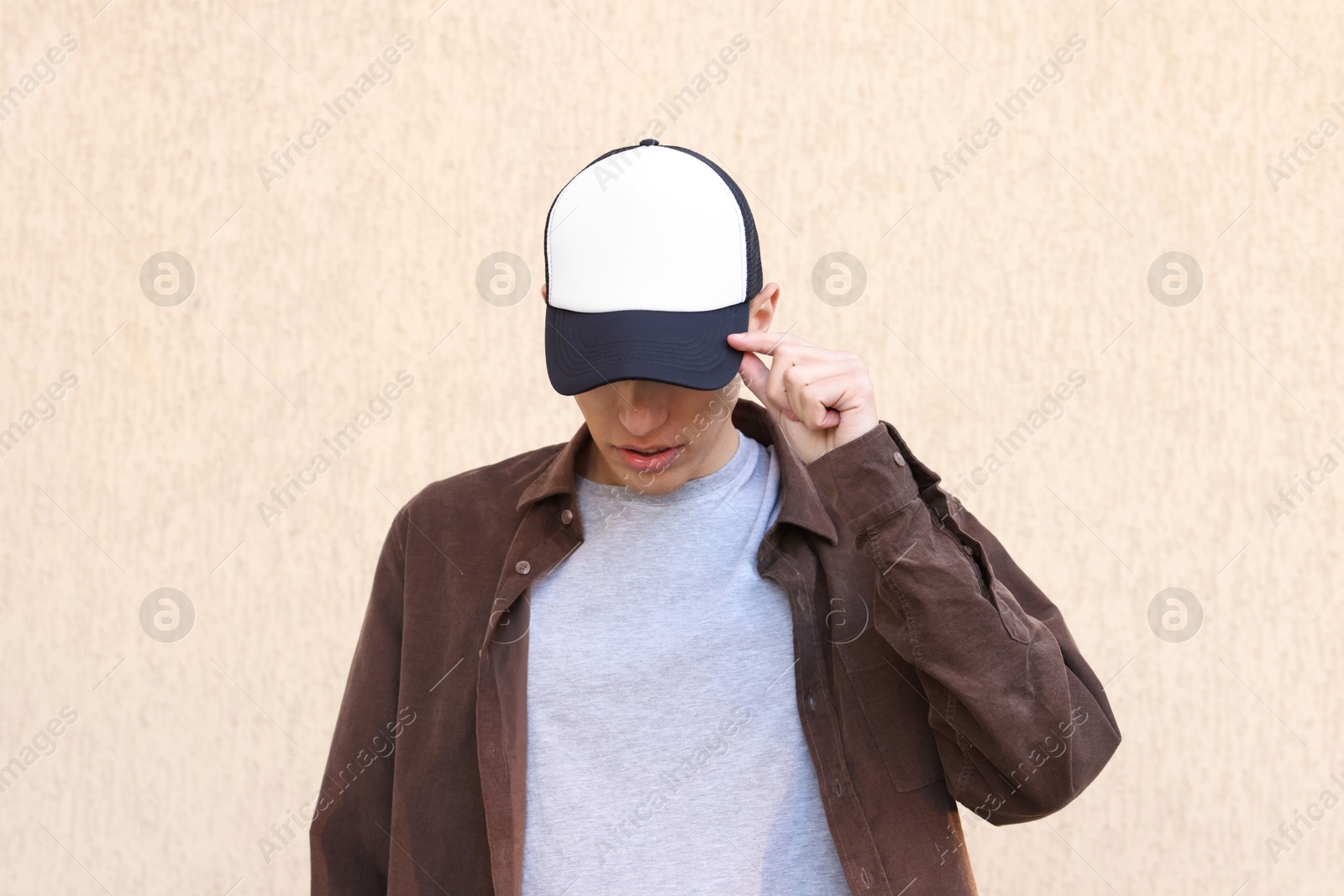 Photo of Man in stylish baseball cap near beige wall. Mockup for design