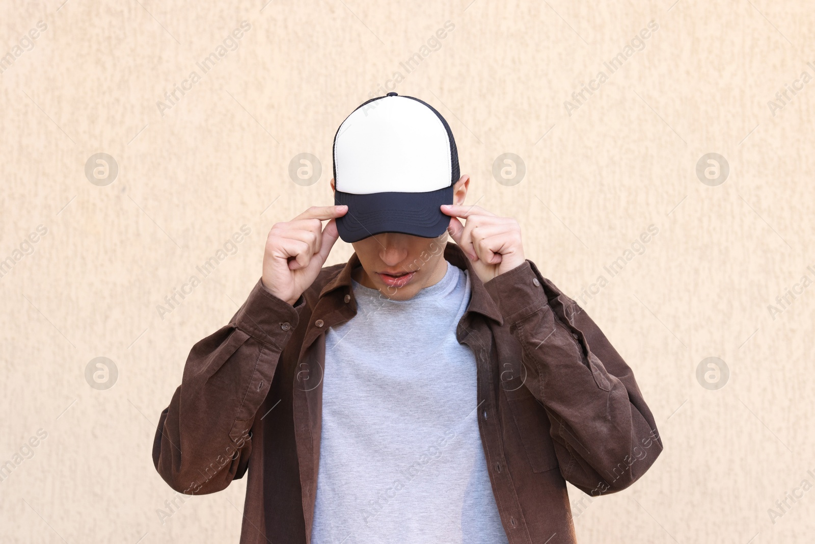 Photo of Man in stylish baseball cap near beige wall. Mockup for design