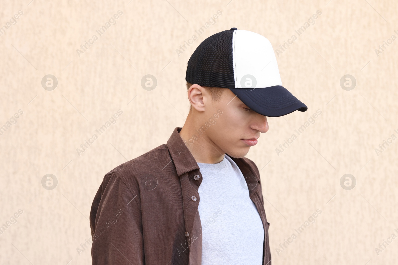 Photo of Man in stylish baseball cap near beige wall. Mockup for design