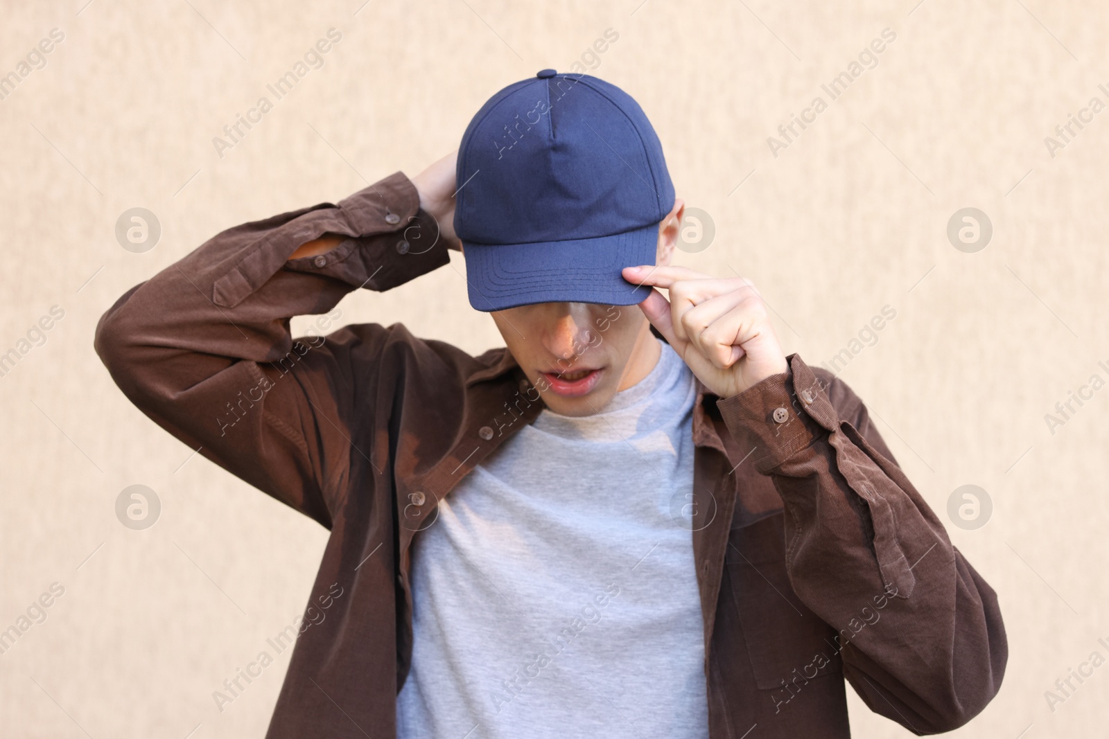 Photo of Man in stylish baseball cap near beige wall. Mockup for design