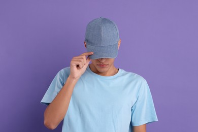 Photo of Man in stylish baseball cap on violet background. Mockup for design