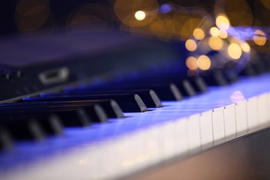 Photo of Piano against blurred lights, closeup. Bokeh effect