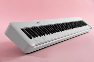 Photo of Synthesizer on pink background, closeup. Electronic musical instrument