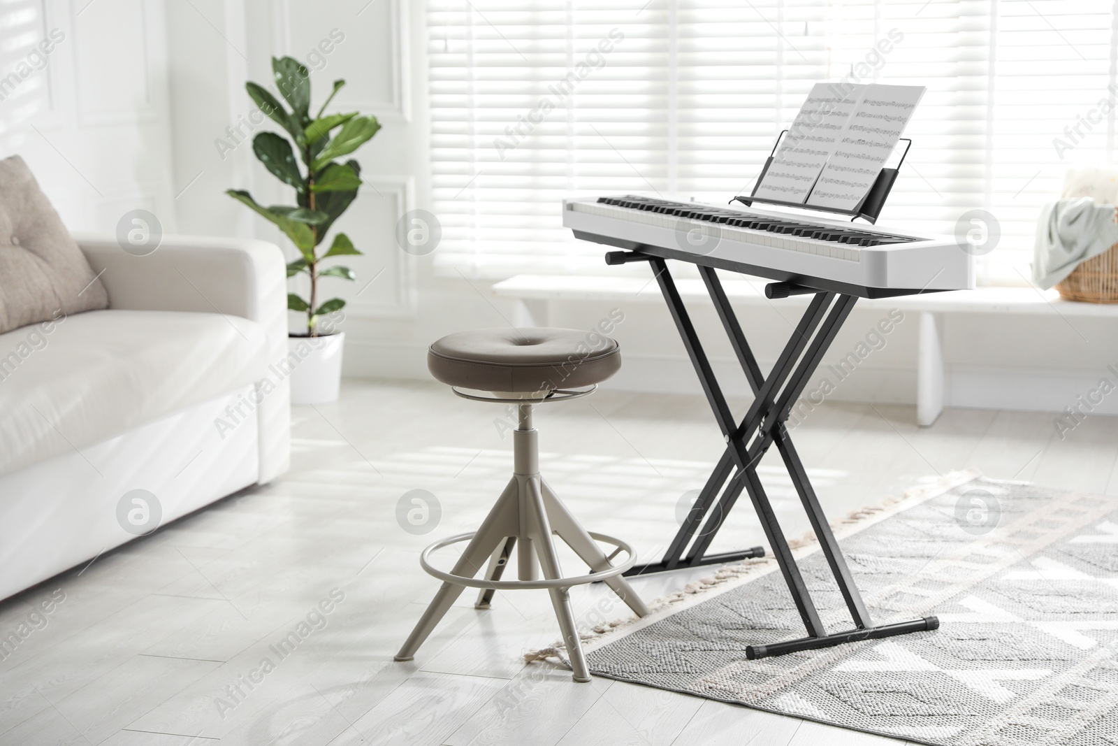 Photo of Synthesizer with music sheets and stool at home