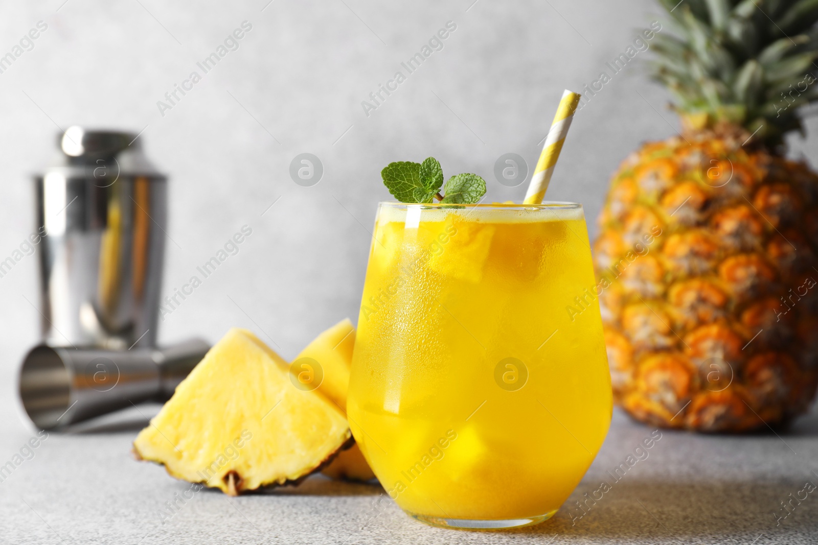 Photo of Tasty pineapple cocktail with mint in glass on gray table