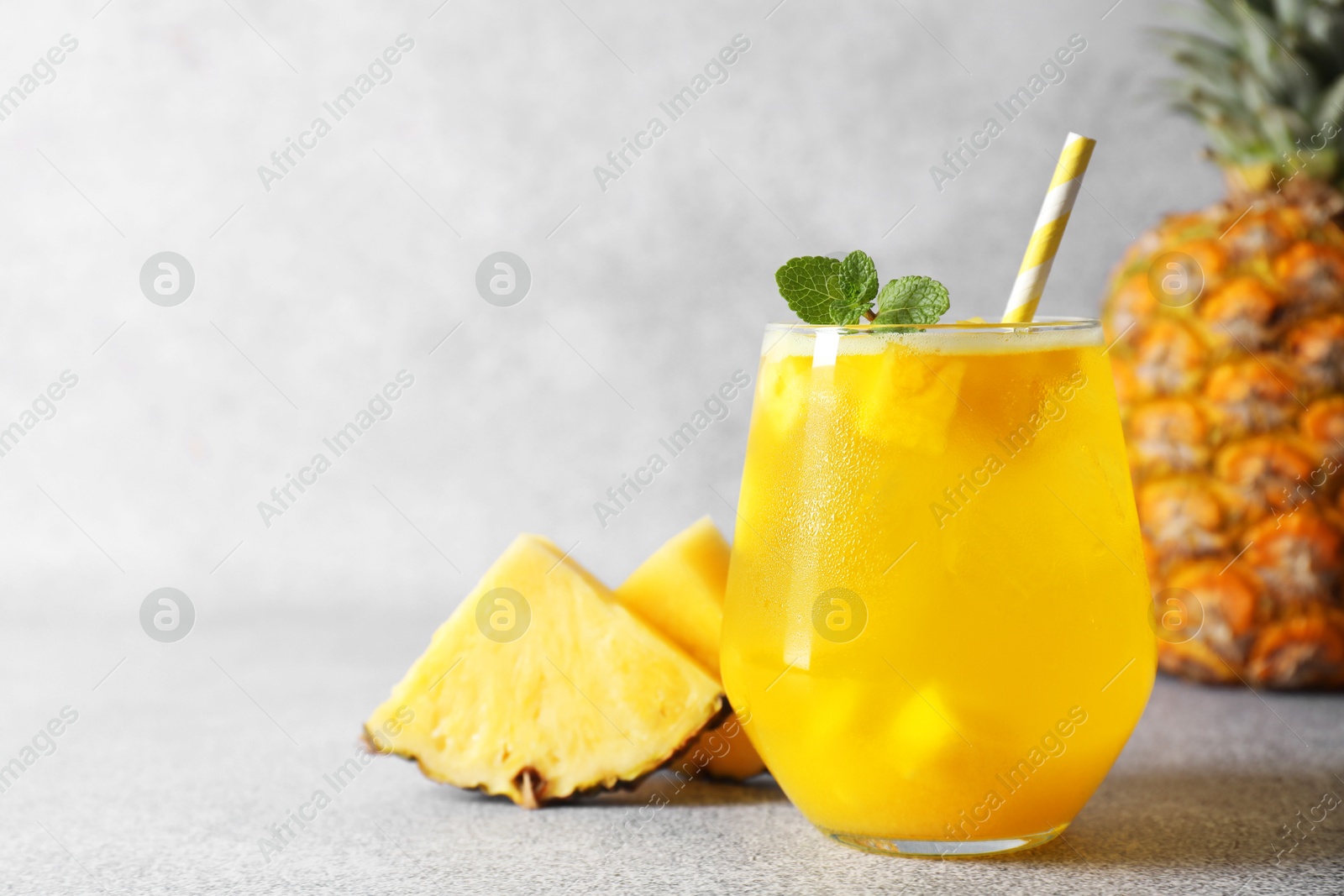 Photo of Tasty pineapple cocktail with mint in glass on gray table, space for text