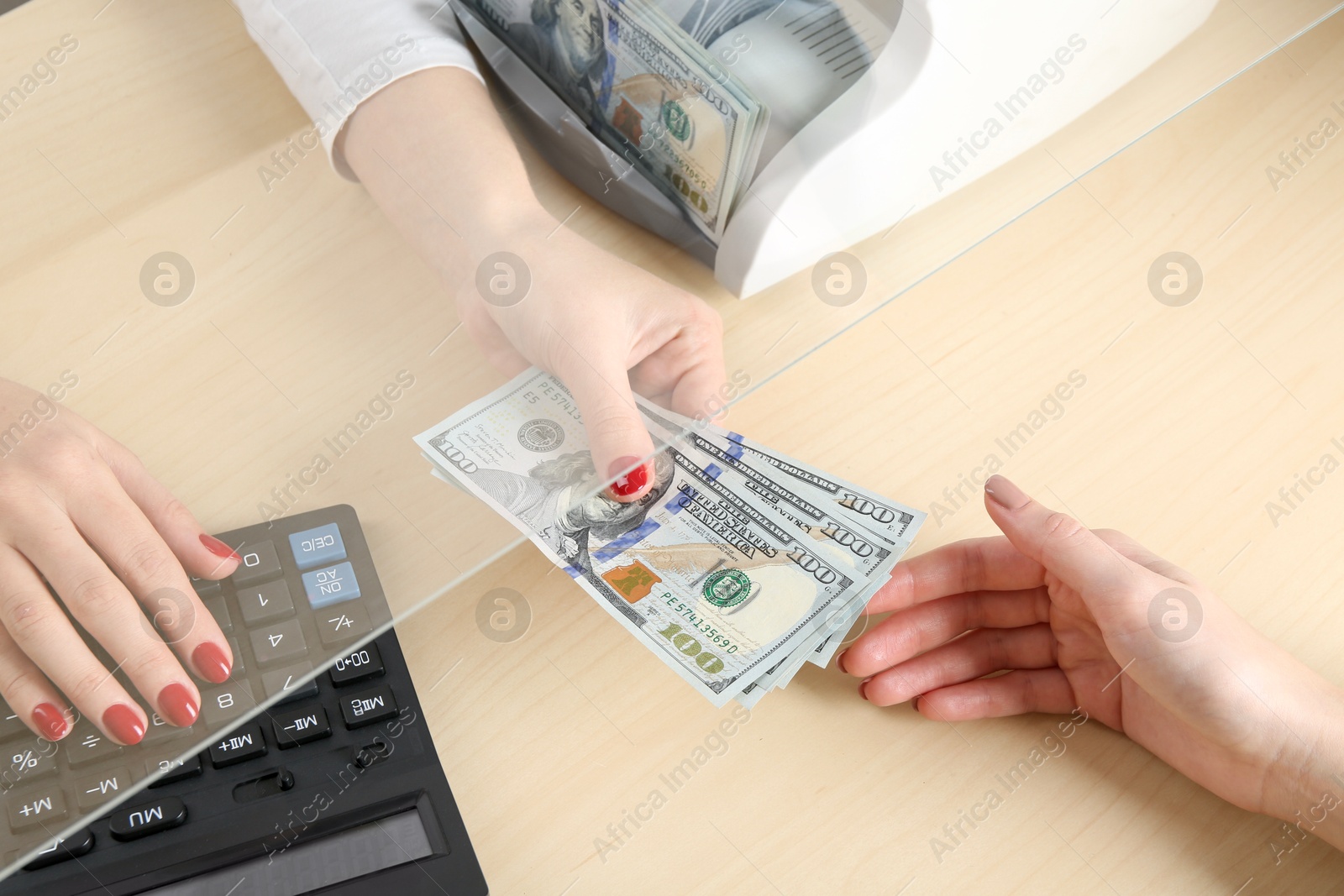 Photo of Cashier giving dollar banknotes to client at table in money exchange, closeup