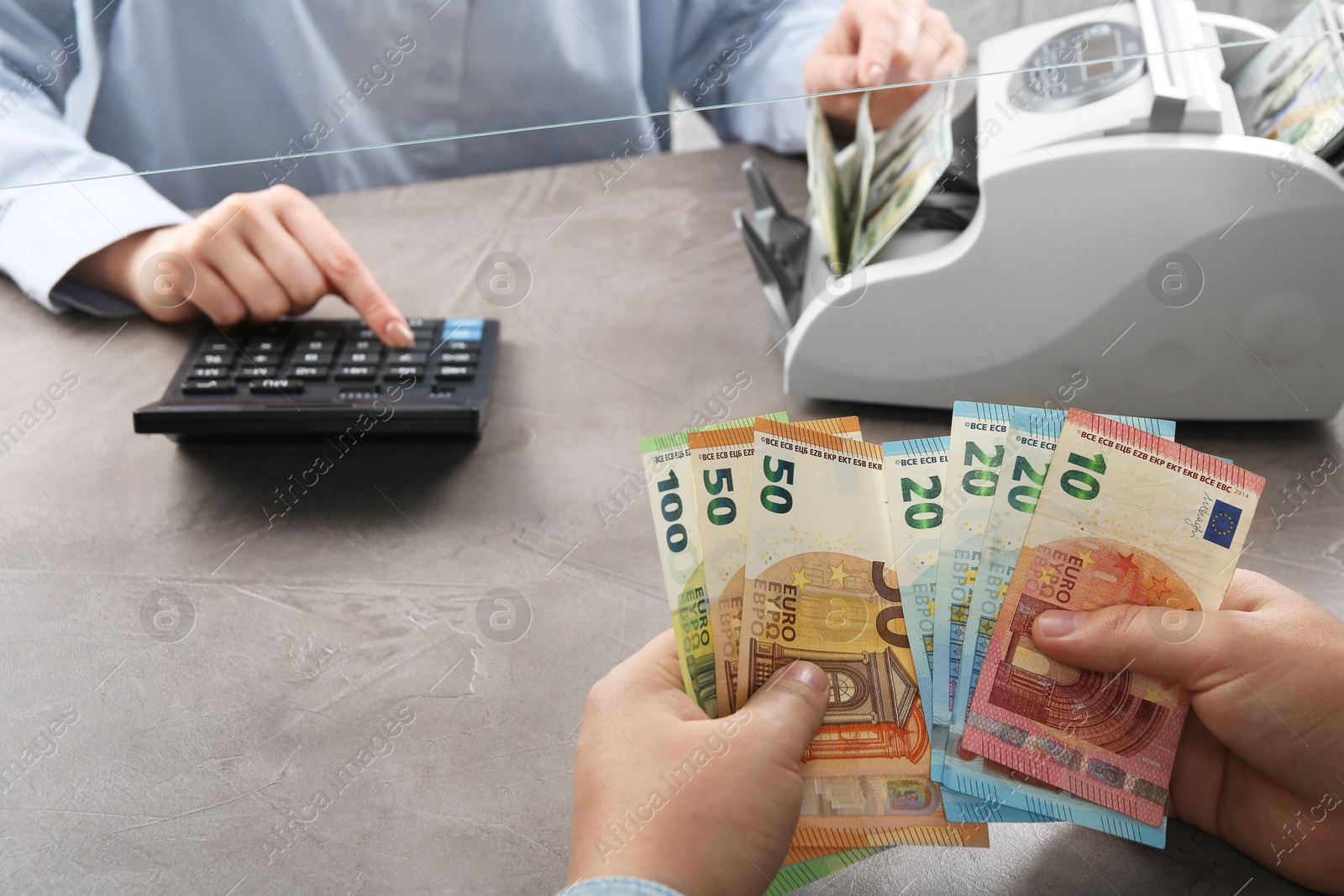 Photo of Client counting money at table in currency exchange, closeup