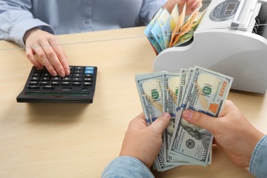 Photo of Client counting money at table in currency exchange, closeup