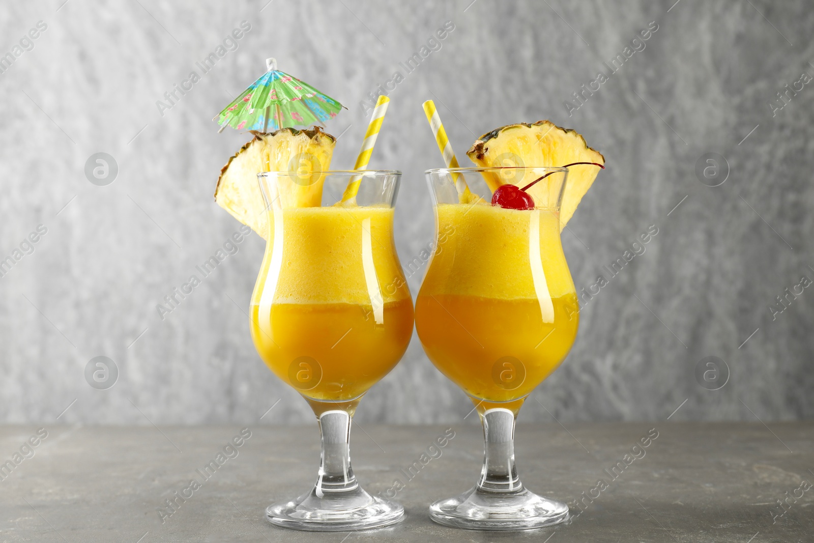 Photo of Tasty pineapple cocktail in glasses served on grey table