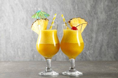 Photo of Tasty pineapple cocktail in glasses served on grey table