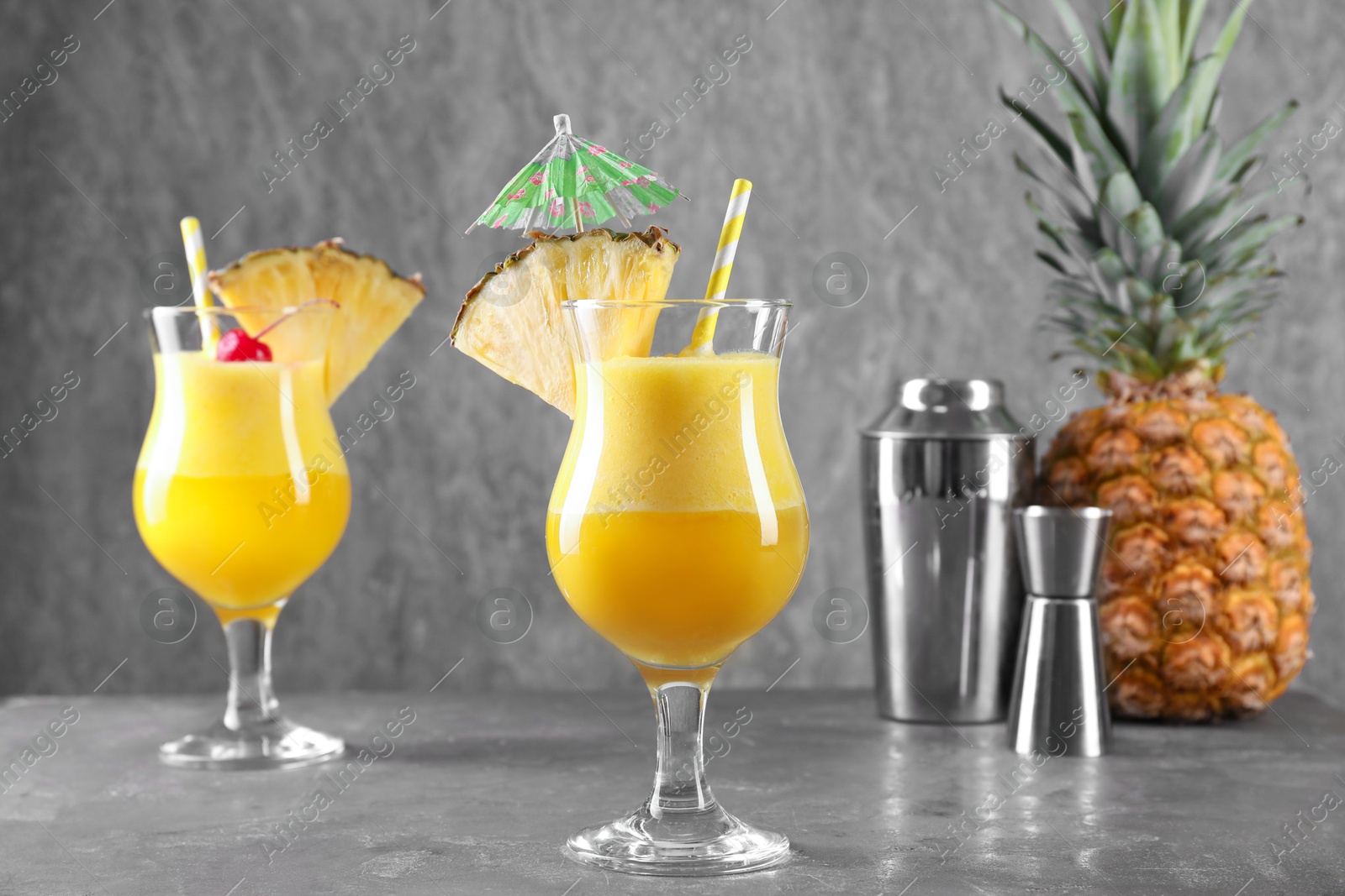 Photo of Tasty pineapple cocktail in glasses served on grey table