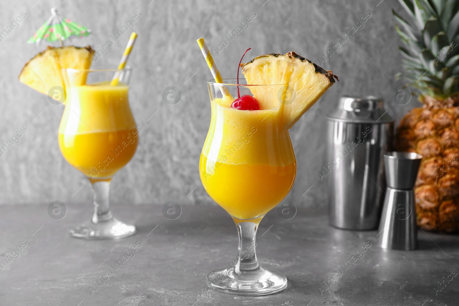 Photo of Tasty pineapple cocktail in glasses served on grey table