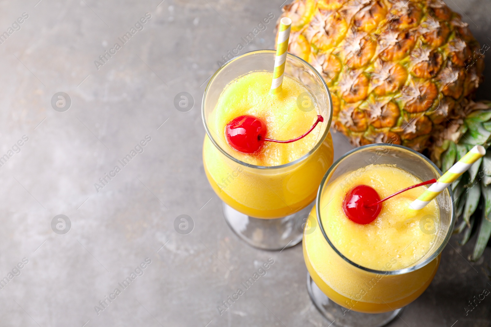 Photo of Tasty pineapple cocktail in glasses served on grey table, above view. Space for text