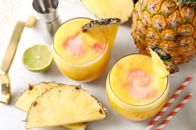 Photo of Tasty pineapple cocktail in glasses served on white table, above view