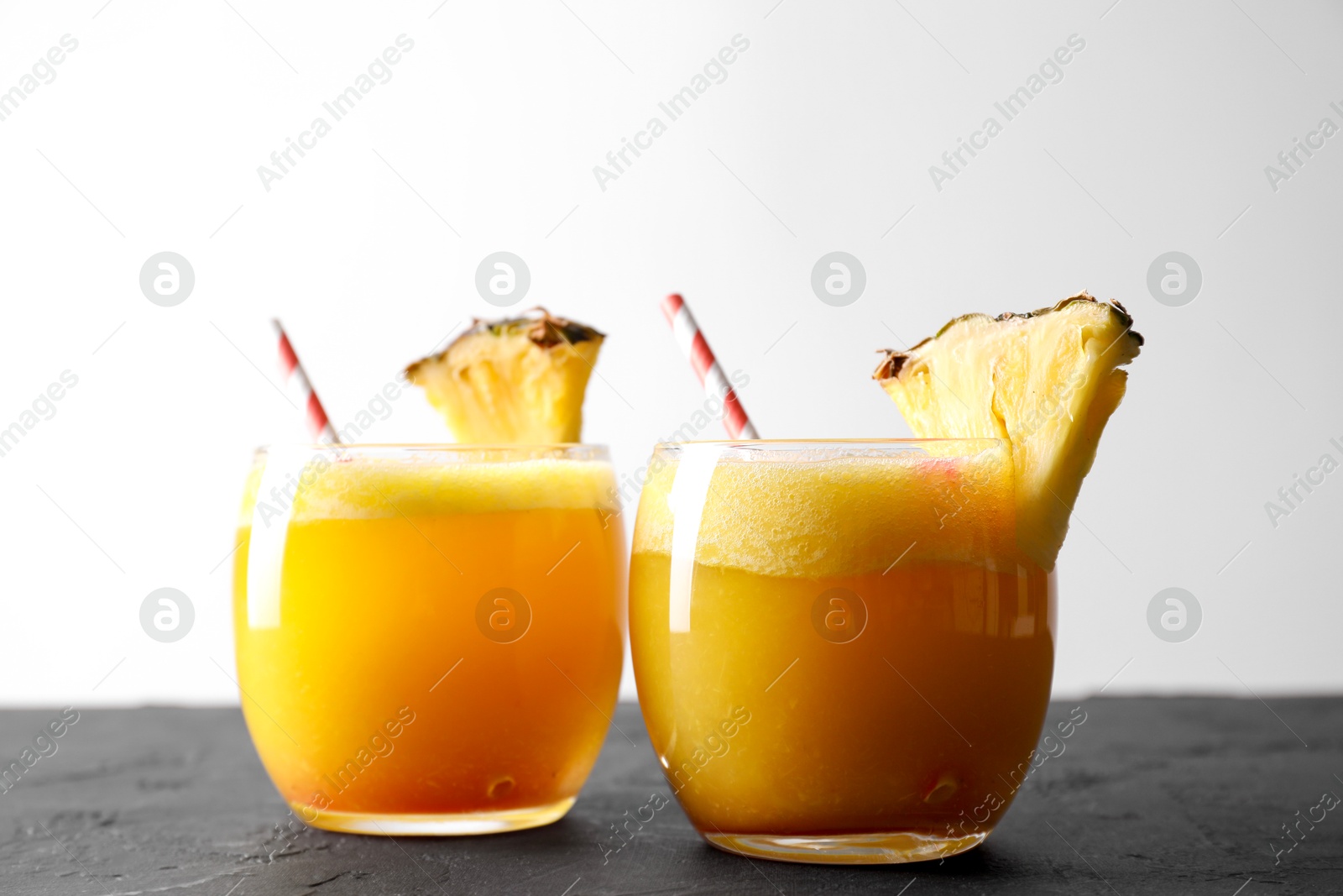 Photo of Tasty pineapple cocktail in glasses served on black table