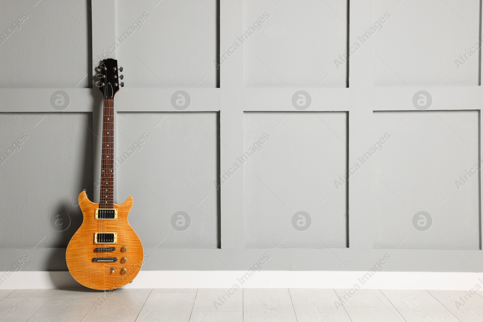 Photo of One modern electric guitar near grey wall. Space for text