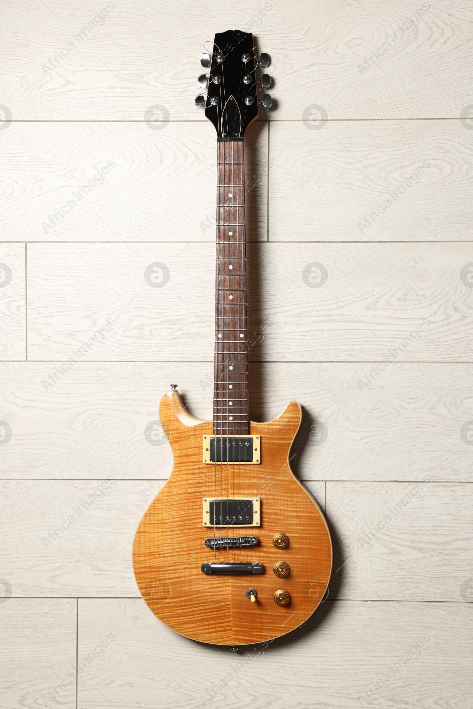 Photo of One modern electric guitar on light wooden background, top view