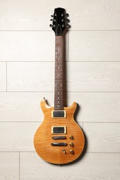 Photo of One modern electric guitar on light wooden background, top view