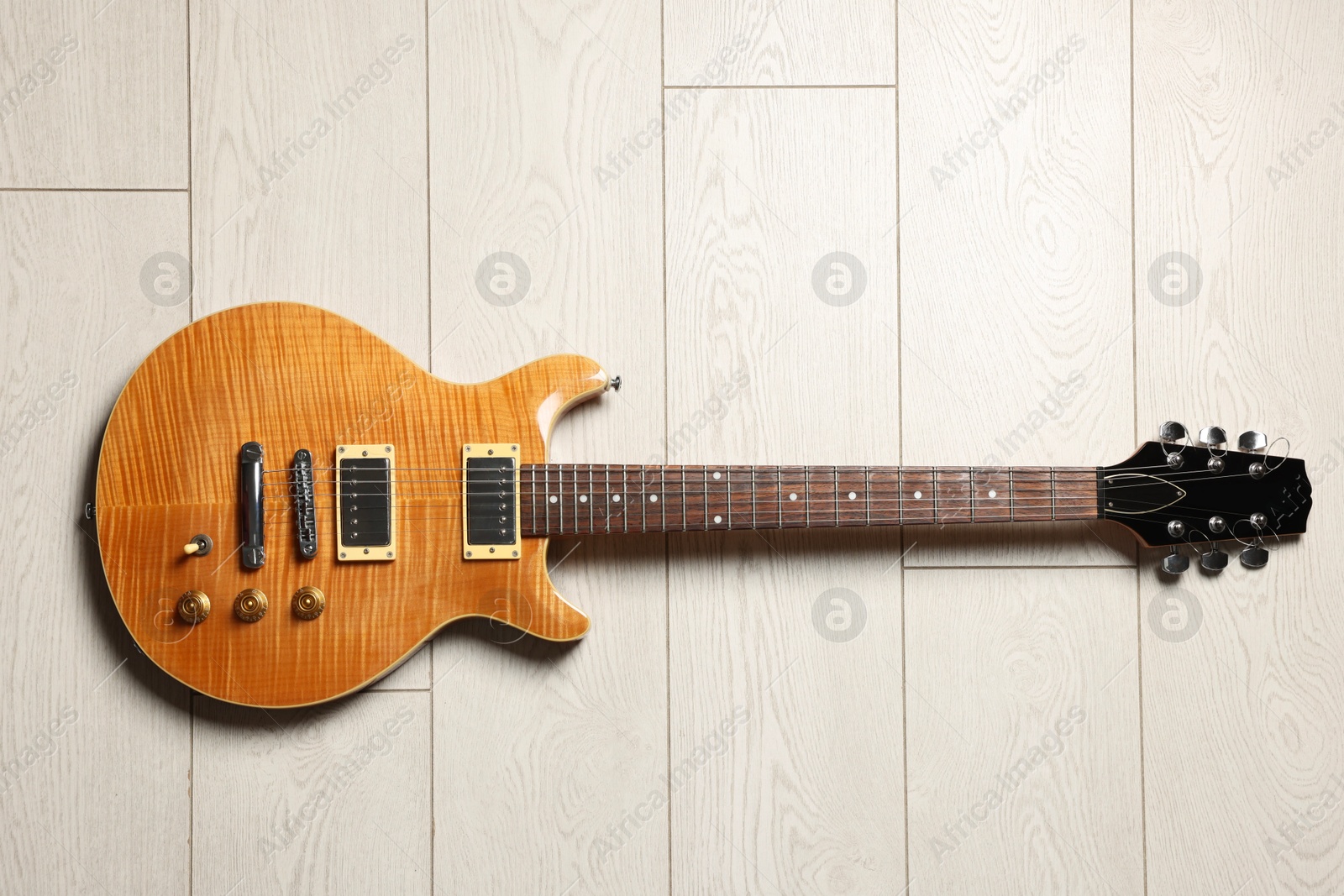 Photo of One modern electric guitar on light wooden background, top view