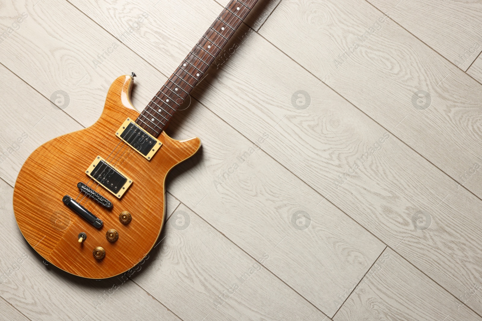 Photo of One modern electric guitar on light wooden background, top view. Space for text