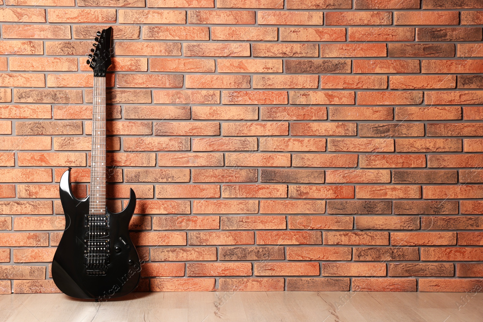 Photo of One modern electric guitar near brick wall. Space for text