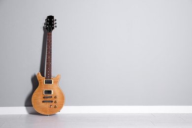 Photo of One modern electric guitar near light grey wall. Space for text