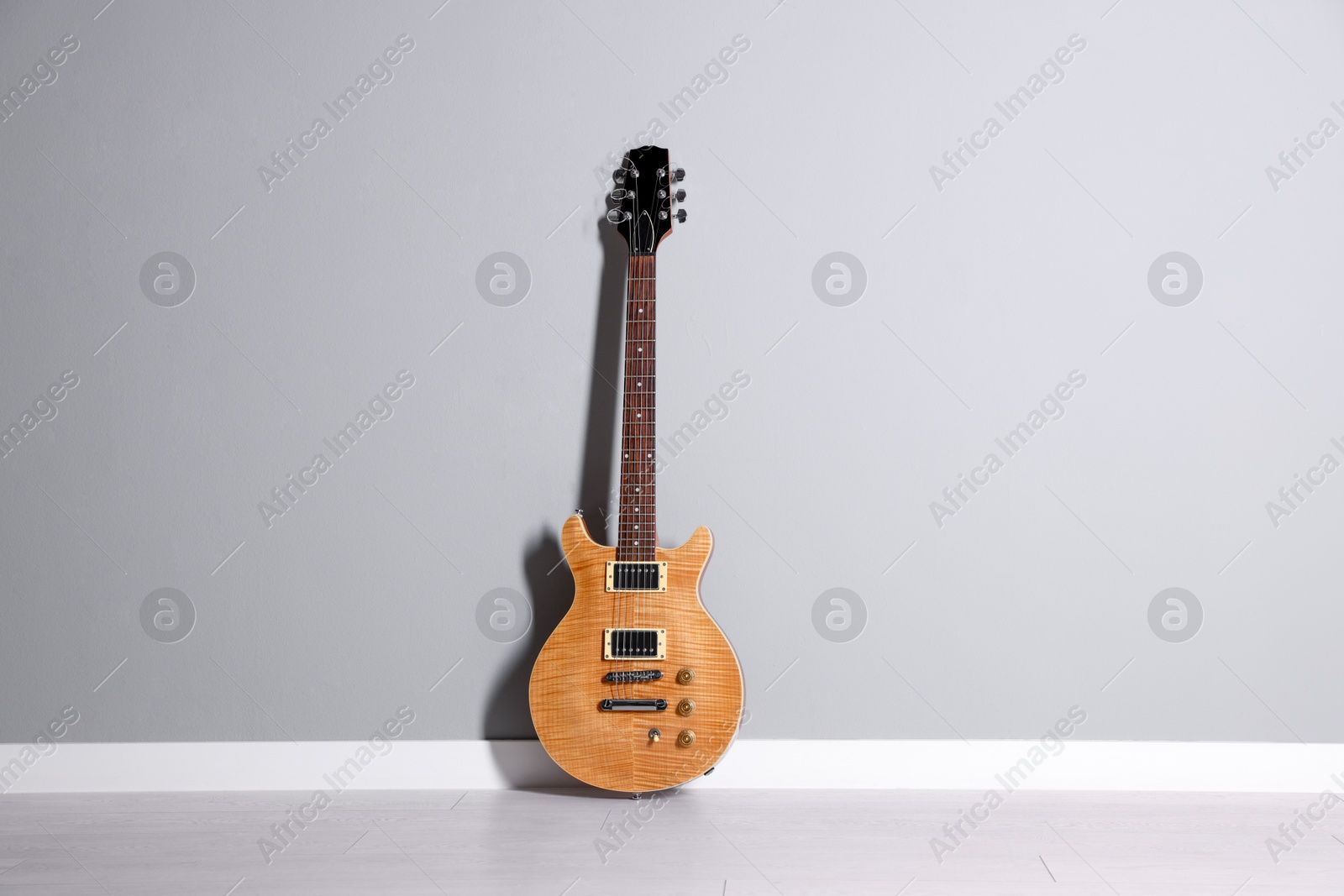 Photo of One modern electric guitar near light grey wall