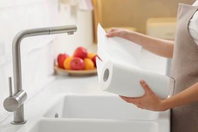 Photo of Woman using paper towels in kitchen, closeup