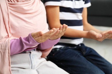 Photo of Muslim girl and boy praying together at home, closeup