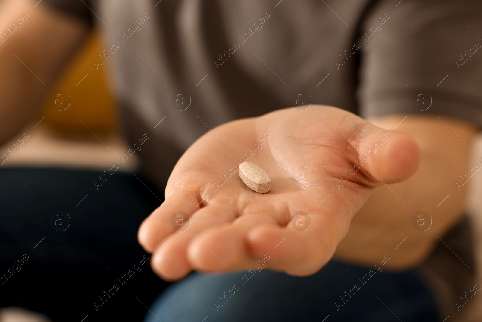 Photo of Man with pill at home, closeup on hand