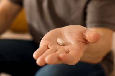 Photo of Man with pill at home, closeup on hand