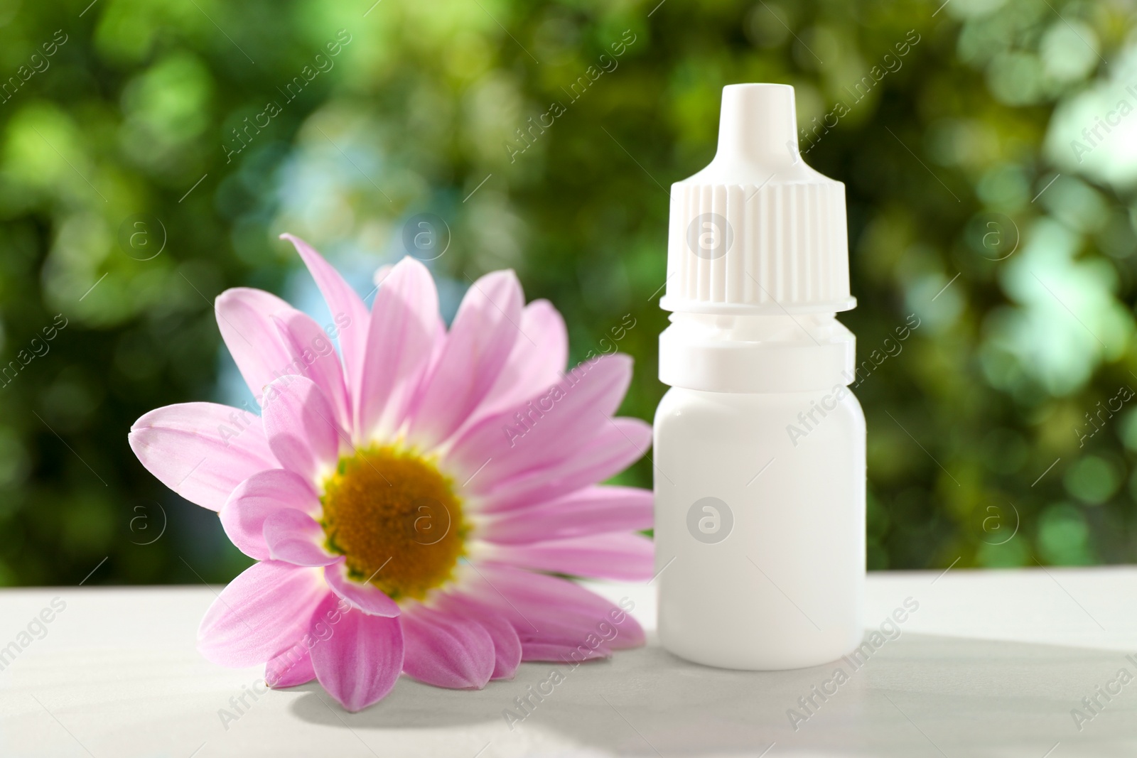 Photo of Allergy treatment. Bottle of medical drops and flower on white table against blurred background, closeup