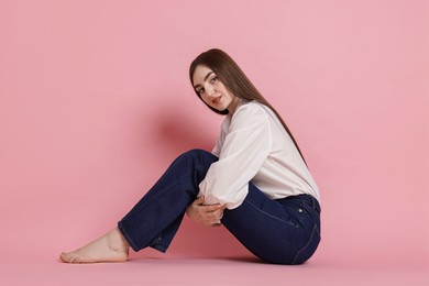 Photo of Beautiful young woman in stylish jeans on pink background